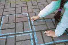 女孩吸引了跳房子粉笔人行道上孩子玩游戏孩子穿毛衣玩跳房子活动孩子们孩子绘画沥青