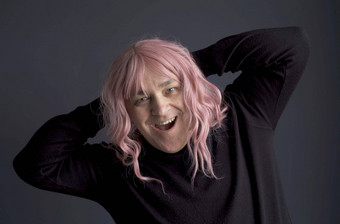 肖像男人。粉红色的假发相机扮鬼脸摆姿势