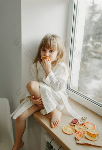 女孩<strong>白色</strong>外套伤心坐着窗台上吃水果棉花糖