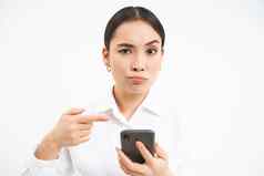 困惑女商人指出手指智能手机持怀疑态度相机不确定信息在线白色背景