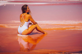 年轻的女人长头发粉红色的咸湖晶体盐极咸粉红色的湖彩色的微藻水晶盐口供水疗中心美健康护理概念
