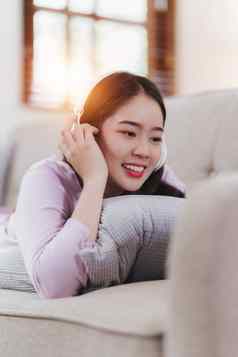 有吸引力的亚洲女人休息舒适的生活房间移动电话放松沙发生活方式