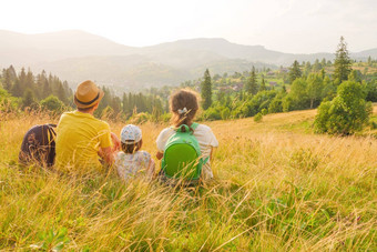 快乐年轻的家庭坐着回来视图山家庭自然假期绿色旅行自然孩子山孩子父母孩子景观孩子绿色周末家庭山旅行自然