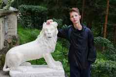 可爱的男孩站石头雕像狮子