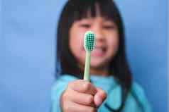 微笑可爱的女孩持有牙刷孤立的蓝色的背景可爱的孩子刷牙牙齿孩子培训口服卫生牙衰变预防牙科护理概念