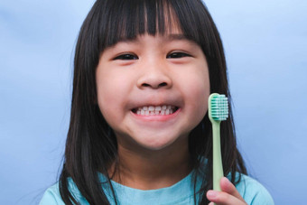 微笑可爱的女孩持有牙刷孤立的蓝色的背景可爱的孩子刷牙牙齿孩子培训口服卫生牙衰变预防牙科护理概念