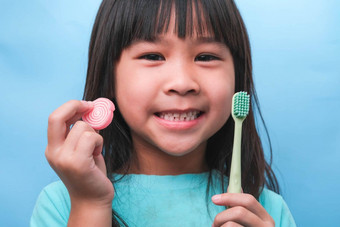 微笑可爱的女孩持有牙刷糖果孤立的蓝色的背景孩子<strong>培训</strong>口服卫生不良的吃牙衰变预防<strong>牙科</strong>护理概念