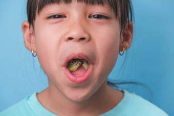 微笑可爱的女孩吃甜蜜的明胶糖添加孤立的蓝色的背景孩子们吃含糖的糖果导致损失牙齿牙衰变不健康的口服护理
