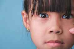 特写镜头肖像惊讶年轻的亚洲女孩孤立的蓝色的背景可爱的震惊了年轻的女孩大黑色的眼睛反应令人惊讶的是相机负情绪孩子