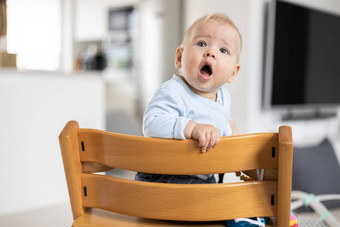 快乐<strong>婴</strong>儿坐着传统的斯堪的那维亚设计师木高椅子现代明亮的<strong>首页</strong>可爱的<strong>婴</strong>儿