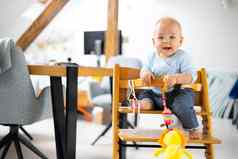 快乐婴儿坐着玩玩具传统的斯堪的那维亚设计师木高椅子现代明亮的atic首页可爱的婴儿