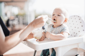 妈妈。勺子喂养婴儿男孩孩子婴儿椅子水果泥<strong>玄关</strong>夏天假期婴儿固体食物介绍概念