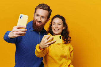 男人。女人夫妇微笑愉快地电话手社会媒体查看照片视频黄色的背景符号迹象手手势家庭自由职业者
