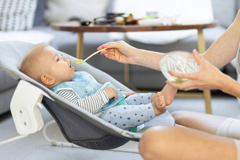 妈妈。勺子喂养婴儿男孩婴儿孩子婴儿椅子<strong>水果泥</strong>婴儿固体食物介绍概念