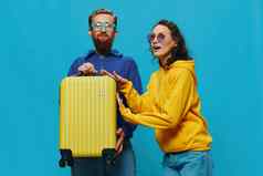 女人男人。微笑坐着手提箱黄色的手提箱微笑蓝色的背景包装旅行家庭假期旅行
