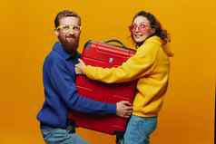 女人男人。微笑手提箱手黄色的红色的手提箱微笑愉快地弯曲的黄色的背景旅行家庭假期旅行新婚夫妇