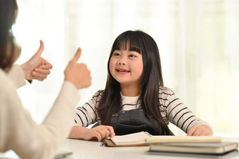 可爱的亚洲女学生家庭作业快乐妈妈。距离教育在家教育概念