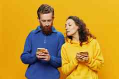 女人男人。快乐的夫妇手机手社会网络沟通弯曲的微笑有趣的战斗黄色的背景概念真正的家庭的关系自由职业者工作在线