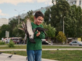 快乐积极的微笑多少数民族十几岁的男孩喂养鸽子广场阳光明媚的春天一天