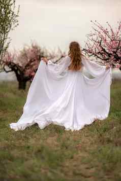 女人桃子开花快乐卷曲的女人白色衣服走花园开花桃子树春天