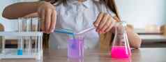 女学生进行实验化学教训女孩倒彩色的液体烧杯