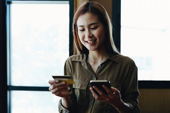 肖像年轻的亚洲女人信贷卡电话在线购物