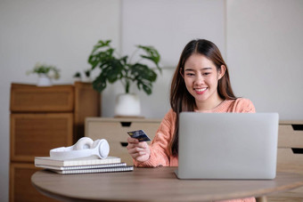 年轻的女人持有信贷卡移动PC电脑女商人工作首页在线购物电子商务互联<strong>网银</strong>行支出钱工作首页概念