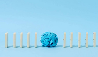 行多米诺骨牌皱巴巴的纸球蓝色的背景