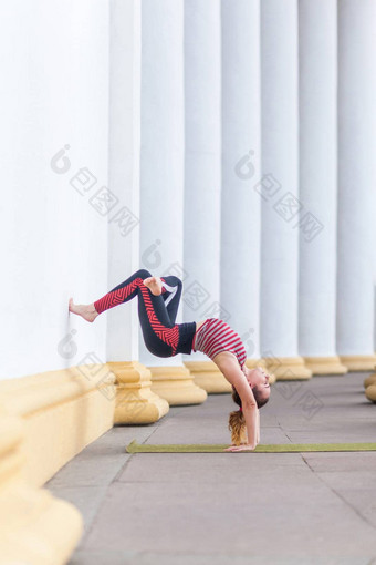 运动强大的瑜珈年轻的成人女人穿运动服装wall-assisted倒立构成瑜伽