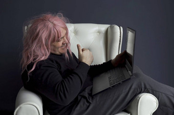 男人。粉红色的假发坐在椅子沟通视频链接