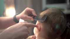 小孩子发型男孩坐着椅子妈妈。切割头发发型理发师机