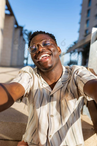 快乐年轻的黑色的男人。眼镜采取自拍相机垂直图像