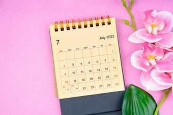 7月日历桌子上粉红色的兰花粉红色的背景