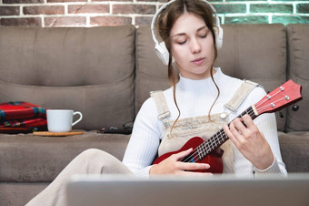 高加索人女孩听音乐<strong>耳机</strong>准备玩吉他尤克里里琴房子坐着地板上移动PC