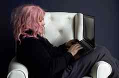 男人。粉红色的假发坐在白色椅子作品电脑