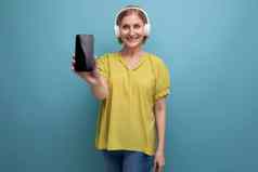 中间岁的业务金发碧眼的女人看视频智能手机耳机声音