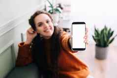 快乐年轻的女人持有移动电话展示空白显示应用程序广告智能手机模型屏幕广告数字应用程序女人的手