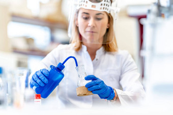 女人进行研究危险的化学物质生化实验室科学研究所保护设备玻璃脸面具橡胶手套