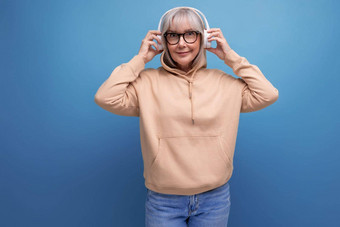 现代奶奶灰色的头发研究听音乐耳机工作室背景复制空间