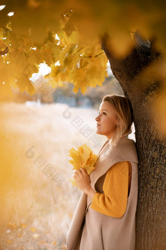 金发女郎站<strong>秋天</strong>树深思熟虑的女人之前穿着黄色的衣服<strong>秋天内容</strong>