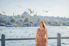 年轻的女人旅行者平克衣服享受伟大的视图横跨博斯普鲁斯海峡很多海鸥伊斯坦布尔