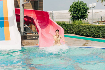 年轻的女人幻灯片池水幻灯片阳光明媚的一天水阿卡公园让人耳目一新热天气活跃的假期健康的生活方式快乐夏天