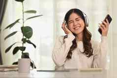 喜出望外亚洲女人听音乐无线耳机享受最喜欢的播放列表人技术生活方式