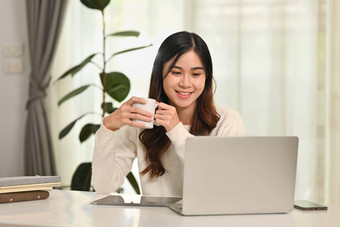 有吸引力的年轻的亚洲女人喝咖啡看视频剪辑阅读电子邮件移动PC人技术生活方式