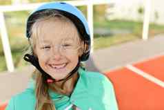 女孩蓝色的头盔辊溜冰鞋体育场