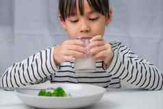可爱的亚洲女孩喝玻璃牛奶早....学校女孩吃健康的蔬菜牛奶餐健康的食物童年