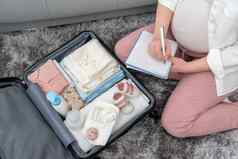 前视图怀孕了女人写作包装列表孕妇医院坐着手提箱