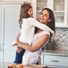 拥抱一天快乐妈妈。拥抱可爱的女孩厨房首页