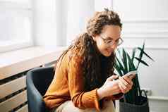 快乐女人浏览现代应用程序移动电话放松女人手机在线购物年轻的女人发短信浏览互联网智能手机家庭放松手机技术