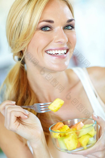 有吸引力的年轻的金发女郎女人享受美味的新鲜的水果沙拉首页